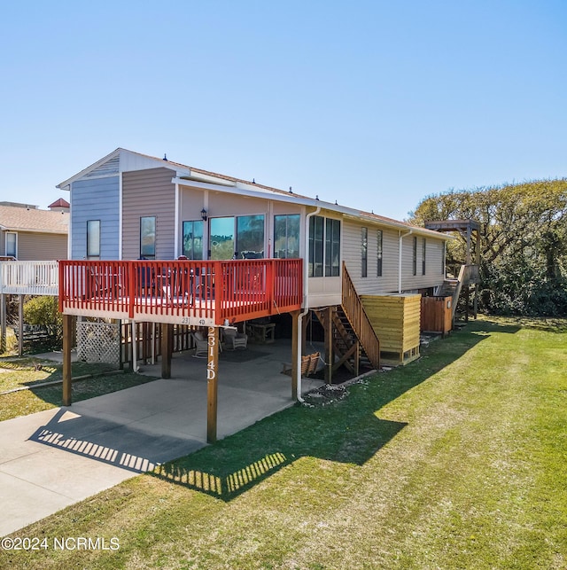 rear view of house featuring a deck, a yard, concrete driveway, and stairs