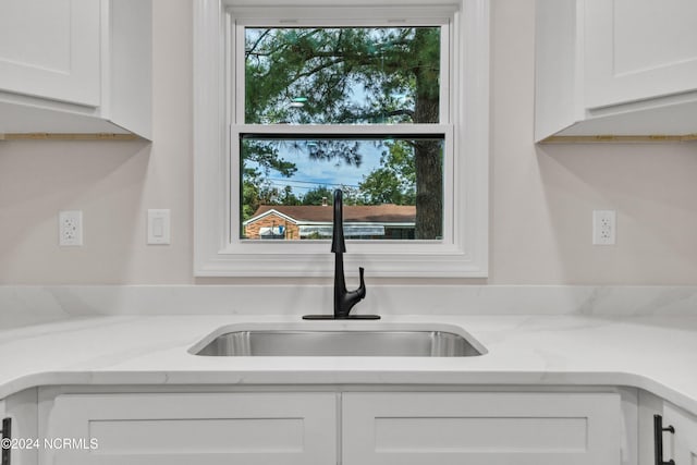 details featuring light stone counters, white cabinets, and sink