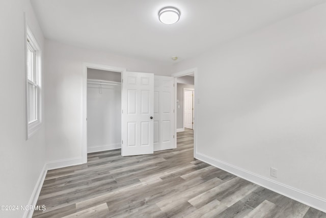 unfurnished bedroom featuring wood finished floors, baseboards, and a closet