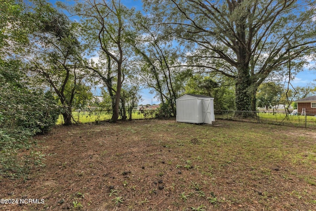 view of yard with fence, an outbuilding, and a storage shed