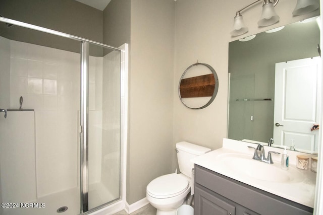 bathroom featuring toilet, a shower with shower door, and vanity