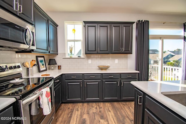kitchen with light countertops, decorative backsplash, wood finished floors, and stainless steel appliances