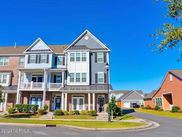 view of property featuring a porch, a front yard, a garage, and a balcony