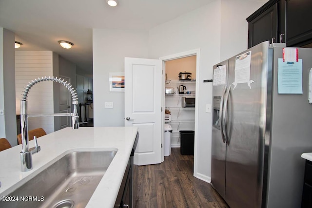 kitchen featuring light countertops, dark wood-style flooring, stainless steel fridge, and a sink