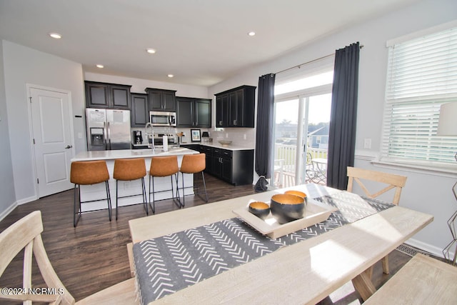 kitchen featuring appliances with stainless steel finishes, dark hardwood / wood-style floors, a center island with sink, and a kitchen bar