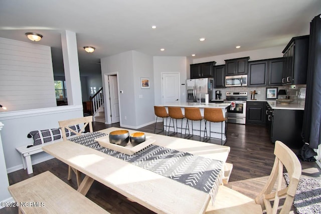 dining area featuring recessed lighting, baseboards, dark wood-style floors, and stairs
