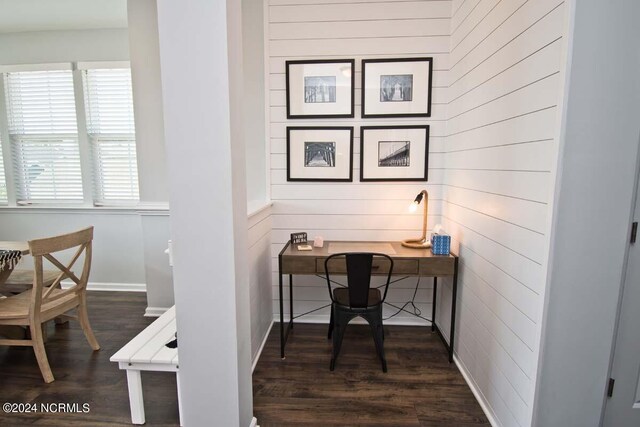 office space featuring baseboards, wood walls, and dark wood-style floors