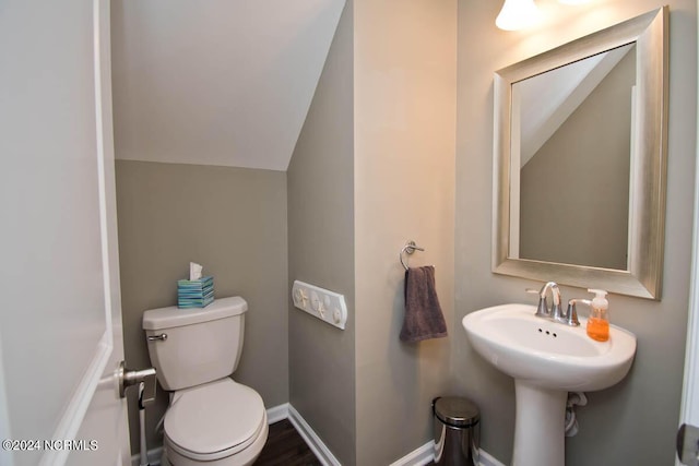 half bathroom with toilet, baseboards, wood finished floors, and lofted ceiling