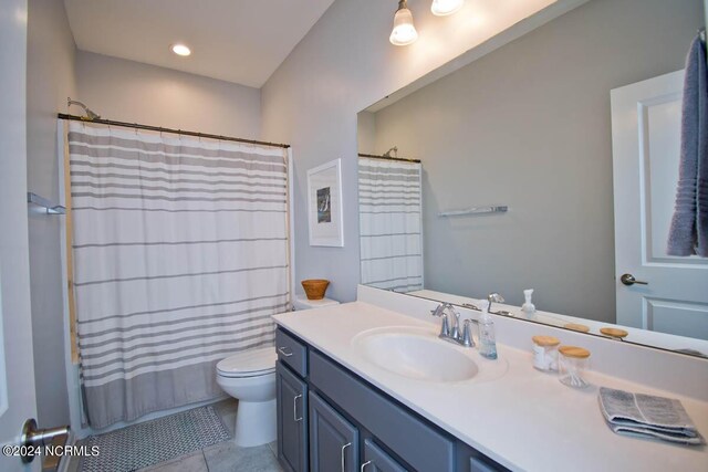 bathroom with tile patterned floors, shower / bathtub combination with curtain, vanity, and toilet