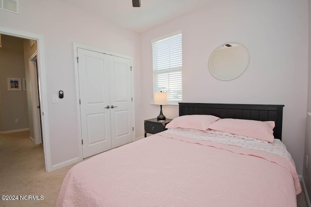bedroom featuring a ceiling fan, light colored carpet, visible vents, baseboards, and a closet