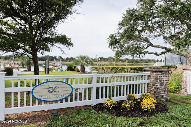 community / neighborhood sign with fence and a water view