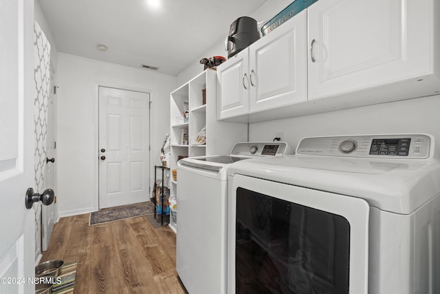 laundry room featuring hardwood / wood-style floors, cabinets, and separate washer and dryer