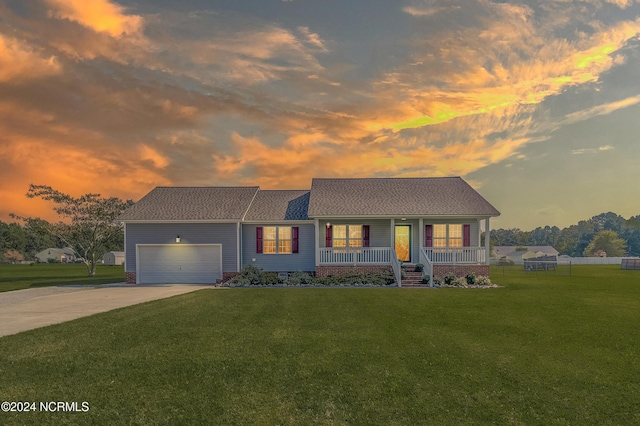 single story home with a porch, a garage, and a lawn