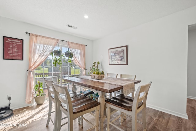 dining space featuring hardwood / wood-style floors and a textured ceiling