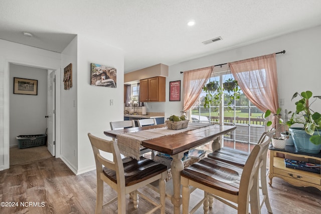 dining room with light hardwood / wood-style flooring and a textured ceiling