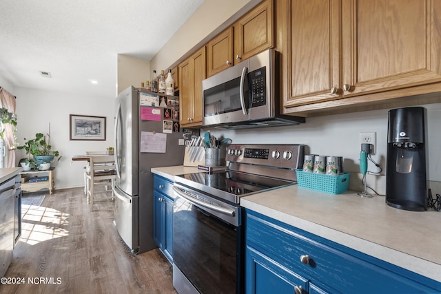 kitchen featuring appliances with stainless steel finishes, a textured ceiling, and dark hardwood / wood-style floors