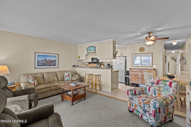 living room featuring ceiling fan, light colored carpet, and a textured ceiling