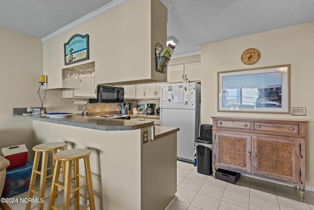 kitchen with white appliances, light tile patterned floors, kitchen peninsula, and a textured ceiling