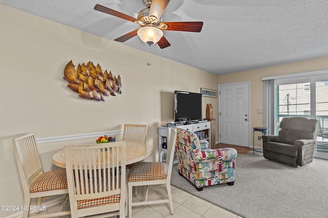 carpeted dining area with ceiling fan and a textured ceiling