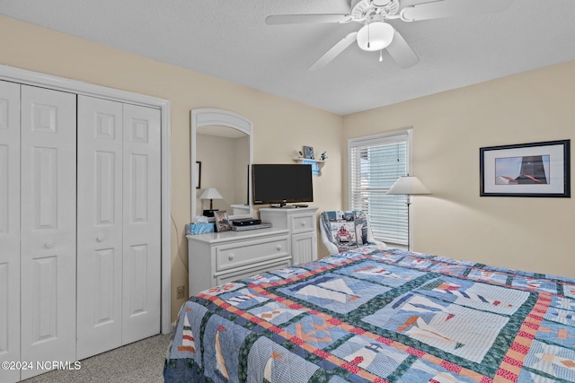 bedroom featuring ceiling fan, a textured ceiling, a closet, and light carpet