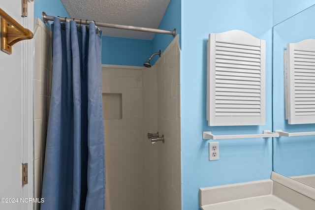 bathroom with curtained shower and a textured ceiling