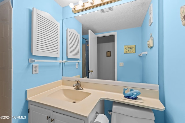 bathroom with vanity, a textured ceiling, and toilet