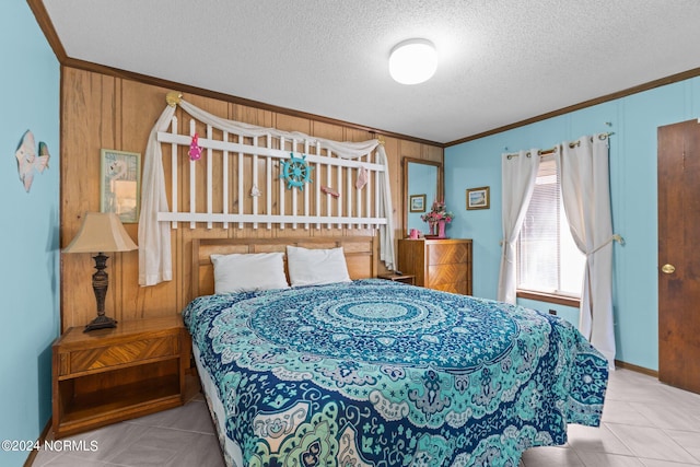 bedroom with ornamental molding, light tile patterned floors, wooden walls, and a textured ceiling