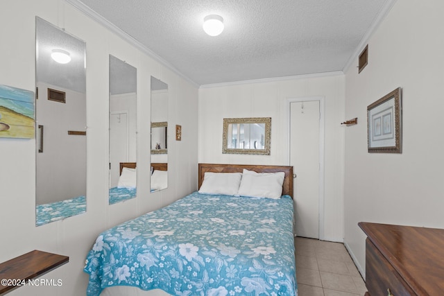 bedroom with crown molding, light tile patterned floors, and a textured ceiling