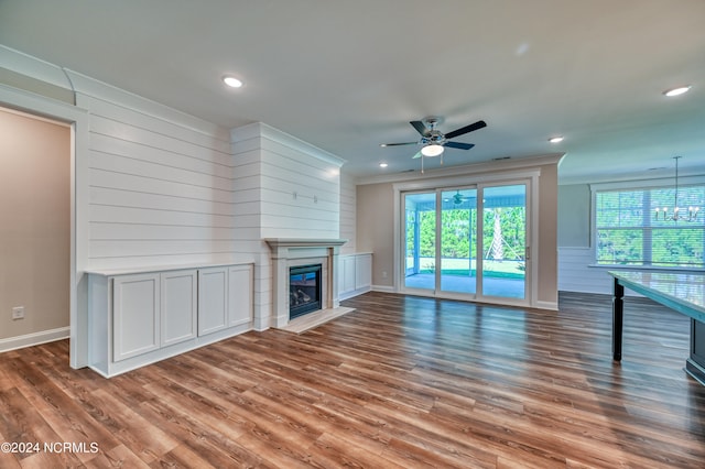 unfurnished living room with ceiling fan with notable chandelier and hardwood / wood-style floors