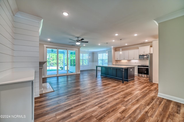 kitchen featuring a kitchen island, decorative light fixtures, white cabinetry, hardwood / wood-style flooring, and stainless steel appliances