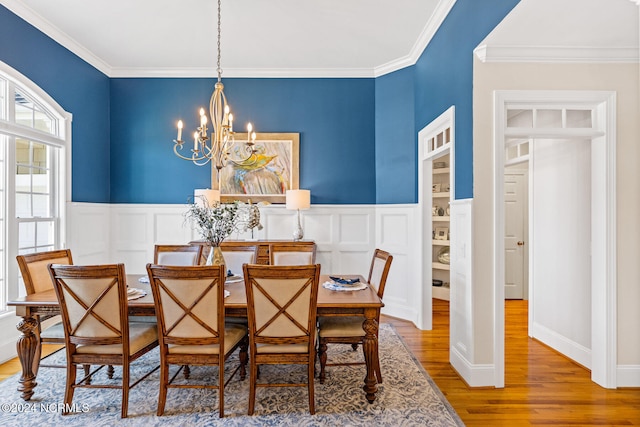 dining space with a notable chandelier, crown molding, and hardwood / wood-style flooring