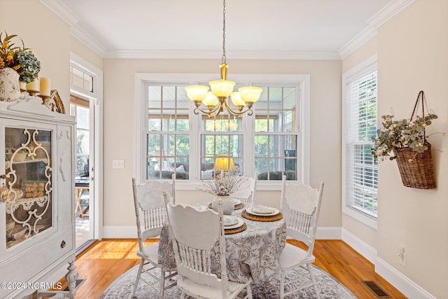 dining room featuring ornamental molding, light wood-type flooring, and a chandelier