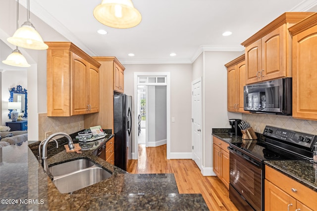 kitchen with light wood-type flooring, pendant lighting, dark stone counters, sink, and black appliances