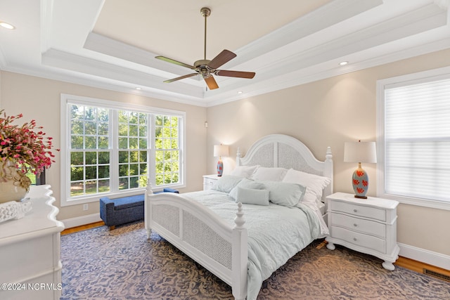 bedroom featuring ceiling fan, hardwood / wood-style flooring, a raised ceiling, and ornamental molding