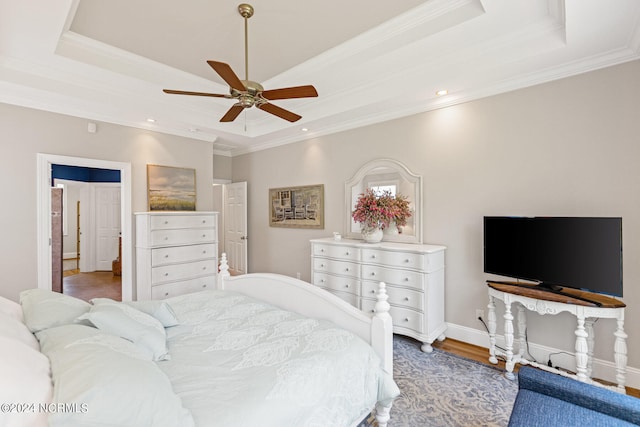 bedroom with ornamental molding, ceiling fan, hardwood / wood-style floors, and a raised ceiling