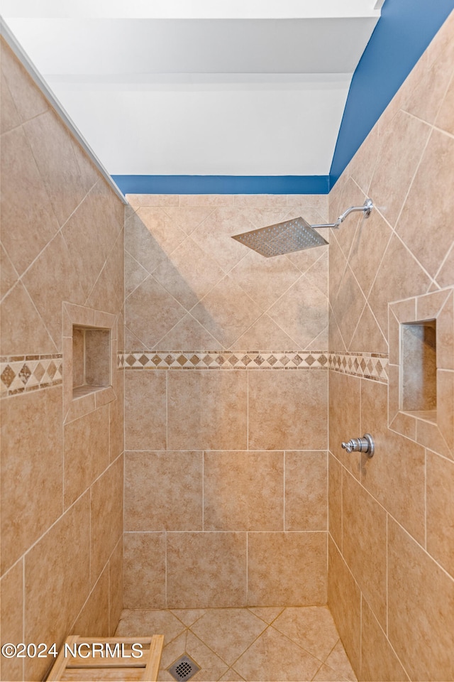 bathroom featuring tile patterned flooring, vaulted ceiling, and tiled shower