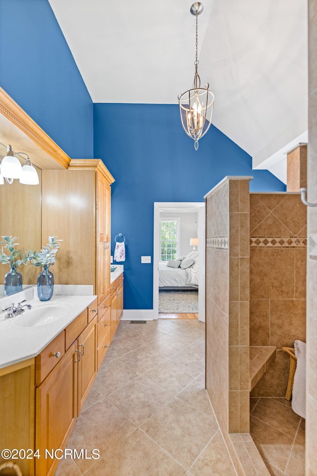 bathroom with high vaulted ceiling, a notable chandelier, tile patterned flooring, and vanity