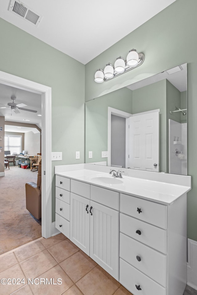 bathroom featuring ceiling fan, vanity, walk in shower, and tile patterned flooring