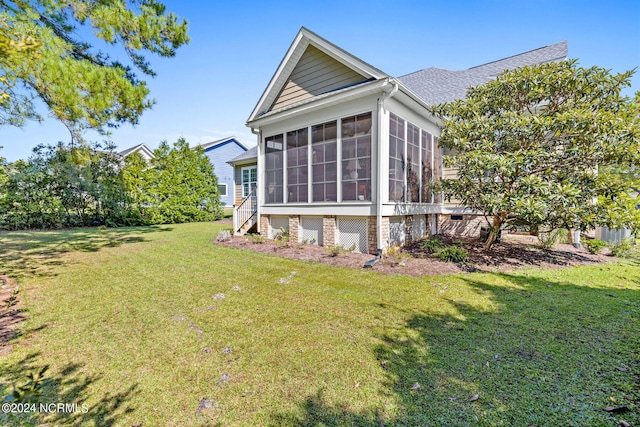 view of home's exterior with a sunroom and a lawn