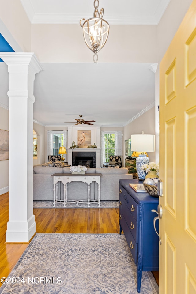 entryway with ceiling fan with notable chandelier, light wood-type flooring, crown molding, and a healthy amount of sunlight