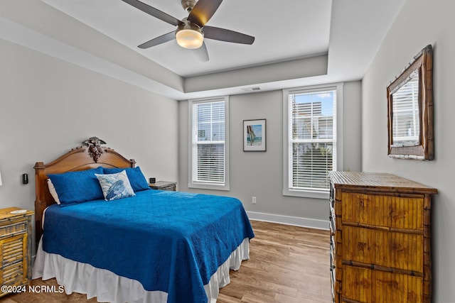 bedroom featuring ceiling fan, hardwood / wood-style floors, and a raised ceiling