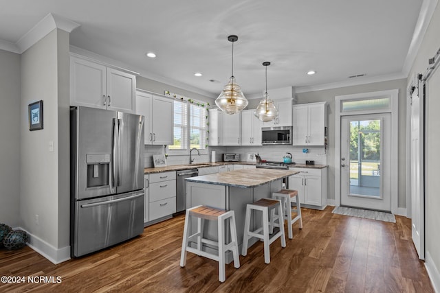 kitchen featuring a center island, a kitchen bar, a barn door, white cabinets, and appliances with stainless steel finishes