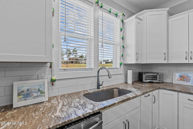 kitchen featuring light stone counters, dishwasher, backsplash, white cabinets, and sink