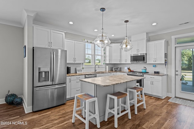 kitchen featuring a kitchen island, a breakfast bar area, white cabinets, appliances with stainless steel finishes, and sink