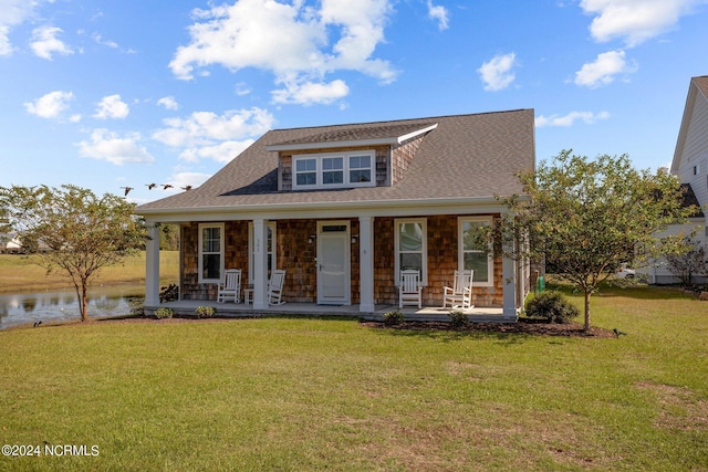 view of front of home with a front yard, covered porch, and a water view