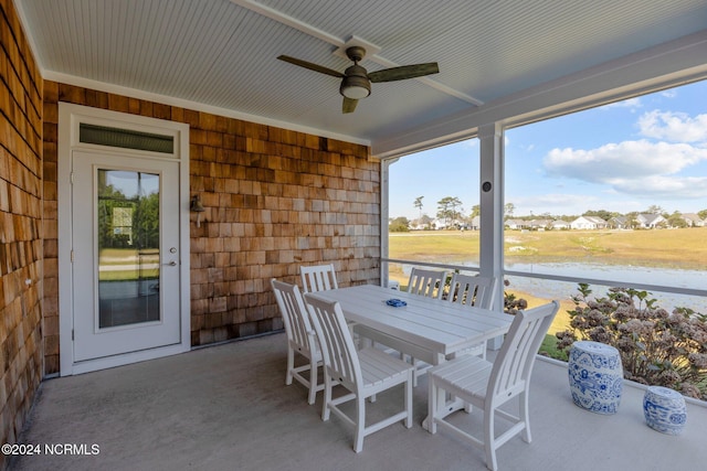 sunroom / solarium with ceiling fan and a water view