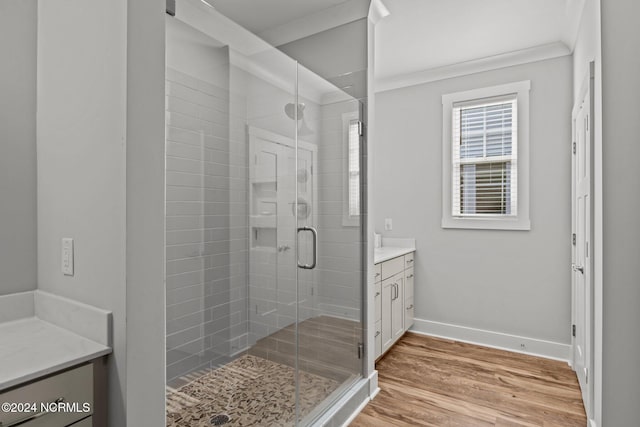 bathroom featuring ornamental molding, wood-type flooring, vanity, and a shower with shower door