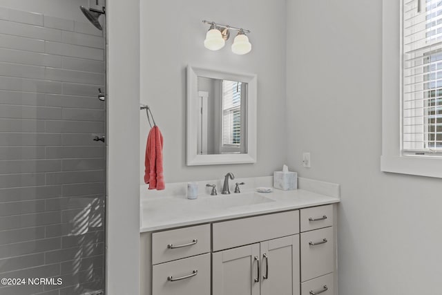 bathroom featuring tiled shower and vanity