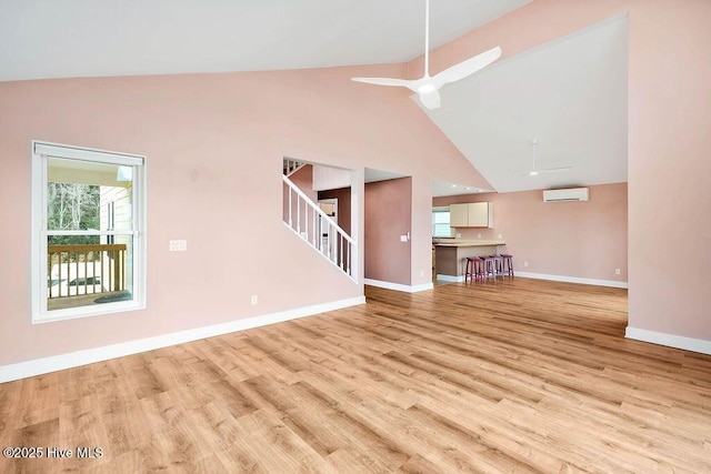 unfurnished living room featuring a wall unit AC, ceiling fan, light hardwood / wood-style flooring, and high vaulted ceiling