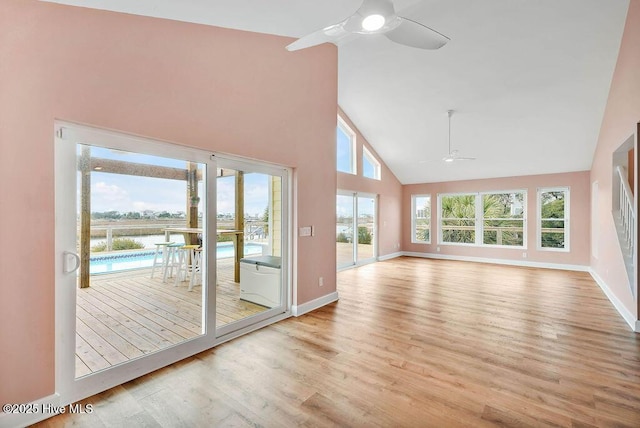 interior space with ceiling fan, light wood-type flooring, a water view, and high vaulted ceiling